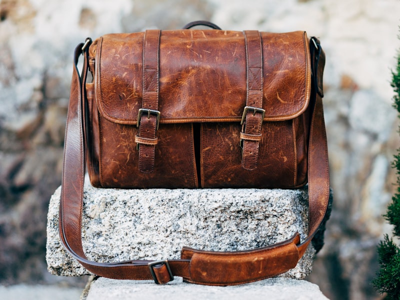 A brown leather satchel bag on concrete